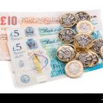 british-one-pound-coins-on-british-bank-notes-JBBWW4